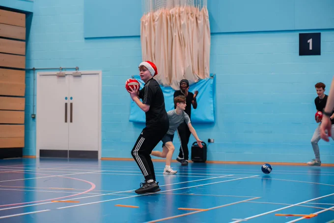 A student wearing a Santa hat playing dodgeball