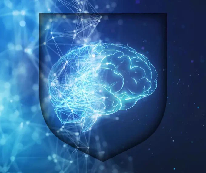 Image depicting a digital illustration of a glowing human brain enclosed within a  shield imprint, The background is a deep blue with network connections.