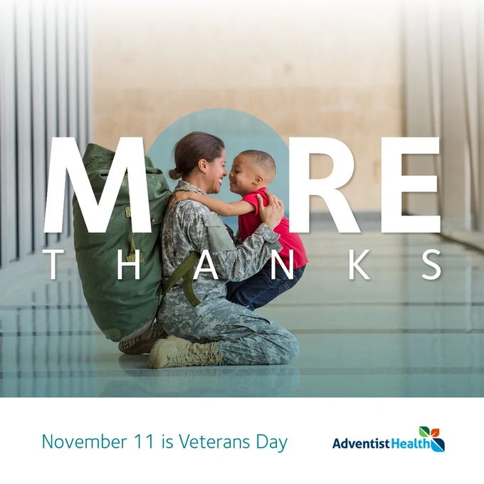 Adventist Health post for Veterans Day featuring a uniformed military person sitting on the floor, affectionately touching foreheads with a young child. Text reads 'MORE Thanks' and 'November 11 is Veterans Day.'