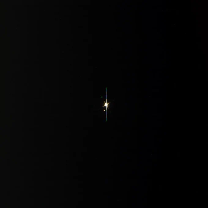 The Earth and Moon seen as two bright white points of light centered against the black background of space.