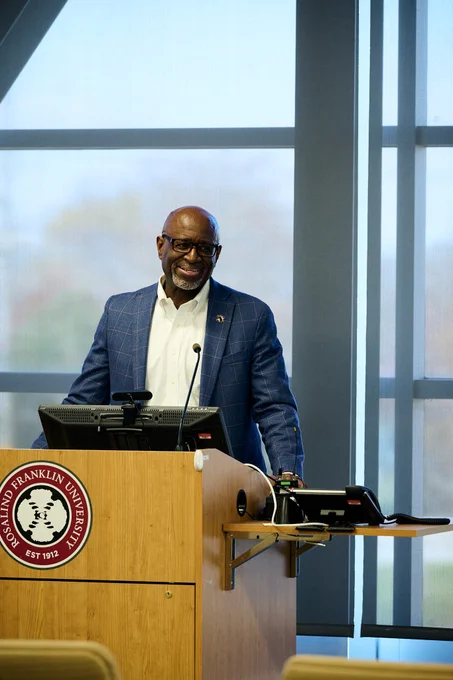 Dr. Eric Williams, VP of Diversity, Equity and Inclusion and a retired veteran, stands behind the podium and smiles