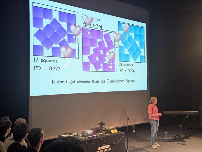 Person on a stage in front of a large projection showing irregular square packings