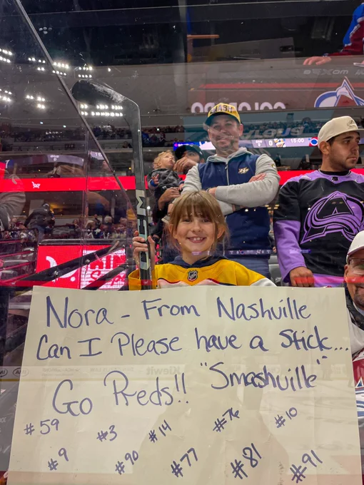 Photo of a fan holding a stick and a sign that says “Nora - from Nashville can I please have a stick. Go Preds!! Smashville”