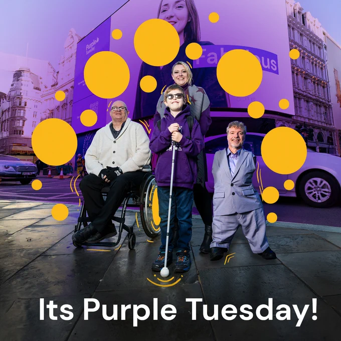 Alt Text: An image of the Purple Tuesday Production on the Picadilly lights, with a young blind man, a man in a wheelchair, a young woman and Mike, founder of Purple Tuesday stood at Picadilly Circus in front of the display with a wave of purple coming out from behind them. Text below them states, "Its purple tuesday!"