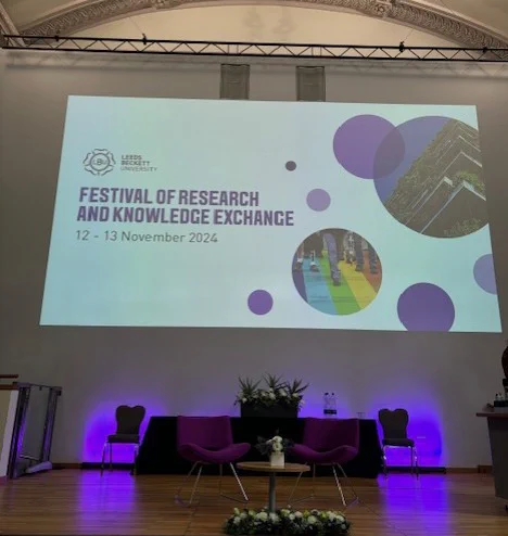 The Great Hall stage with the holding screen saying Festival of Research and Knowledge Exchange
