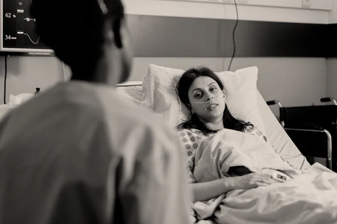 Women lying in a hospital bed with an oxygen machine.
