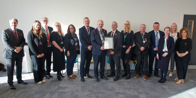A large group of staff stood together holding the gold award certificate