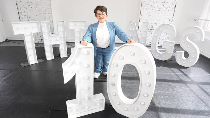 Amy Hassett is standing by cutout lettering spelling 10 THINGS