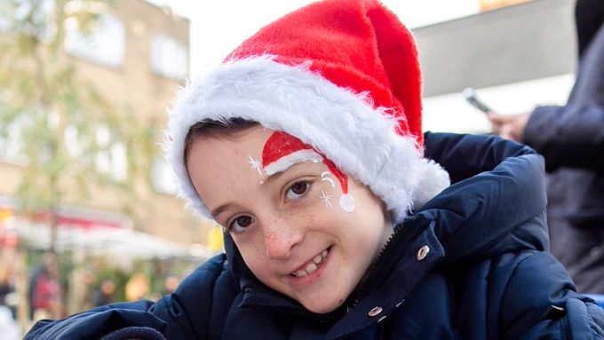 A girl with a santa hat on and santa hat facepaint