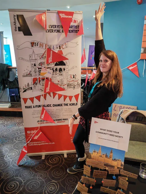 Fun Palaces Director Amie shows off the Fun Palaces exhibition stall decorated in red bunting at Locality convention 2024.