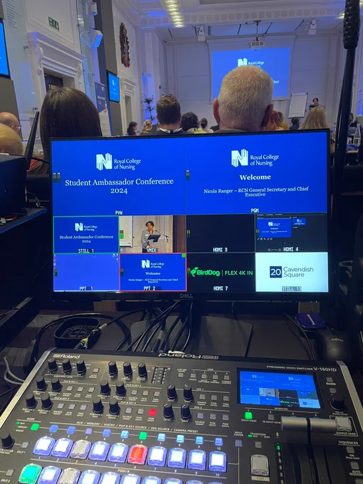 View from behind a technical control setup showing multiple monitors displaying the 'RCN College Student Ambassador Conference 2024'.