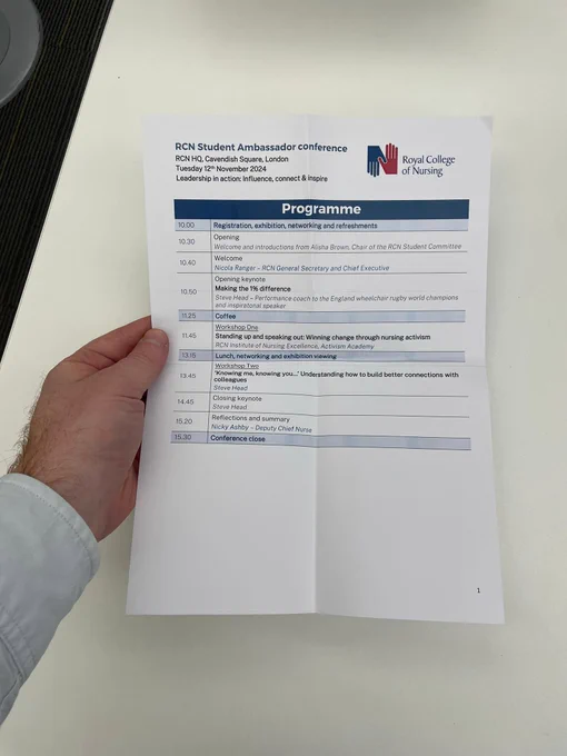 Person holding a printed conference schedule for the Royal College of Nursing Student Ambassador Conference. The schedule includes a list of session times and topics throughout the day.