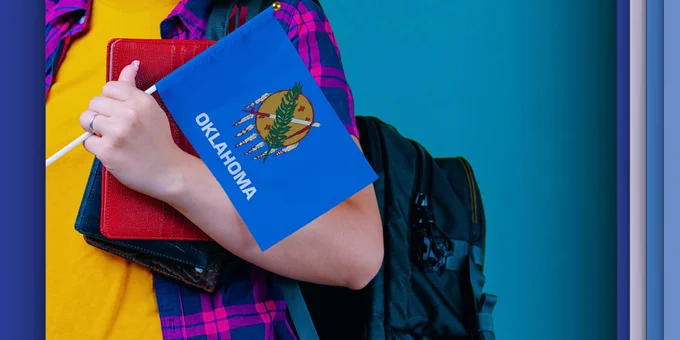 A student holds a tablet and the Oklahoma flag
