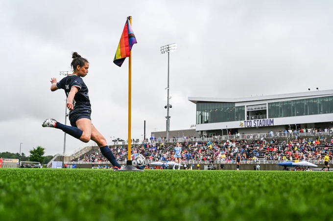 katie duong taking a corner kick with a pride corner flag