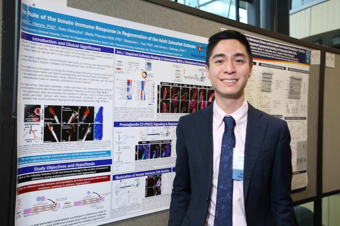 A picture of Jason standing next to their poster presentation during a local symposium at Harvard.