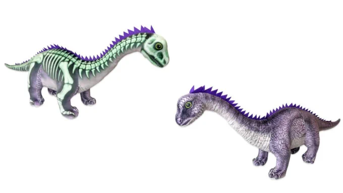 Gnatalie the Green Dino in plush form featuring a green fossil skeleton on one side and purple/gray coloration on the other. Courtesy of NHMLA.