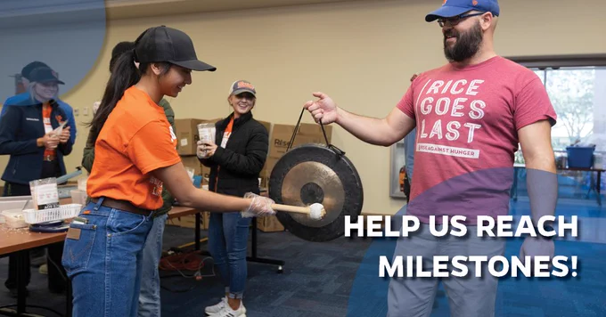 "Help us reach milestones!"

A young woman rings a small gong that an older man stands holding in front of her.