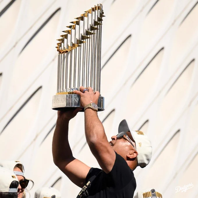 Dave Roberts holds up the World Series trophy while on the bus during the World Series parade.
