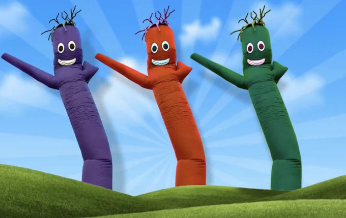 Purple, red, and green 'tube men' dancing on a green field.