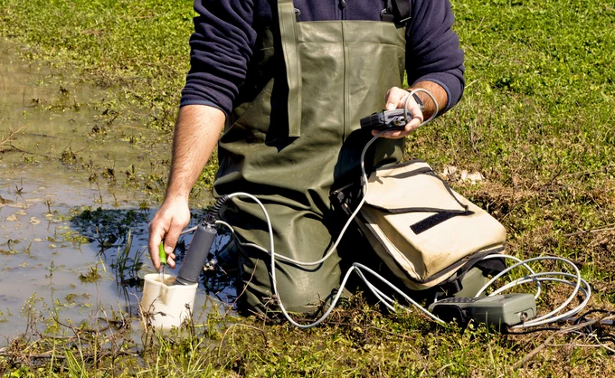 A scientist measuring environmental water quality in a wetland. Stock photo.