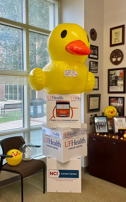 A giant duck sits atop cubes with the UF Health Cancer Center and NCI logos.