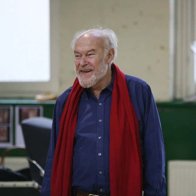 Timothy West in the rehearsal room wearing a blue shirt and red scarf