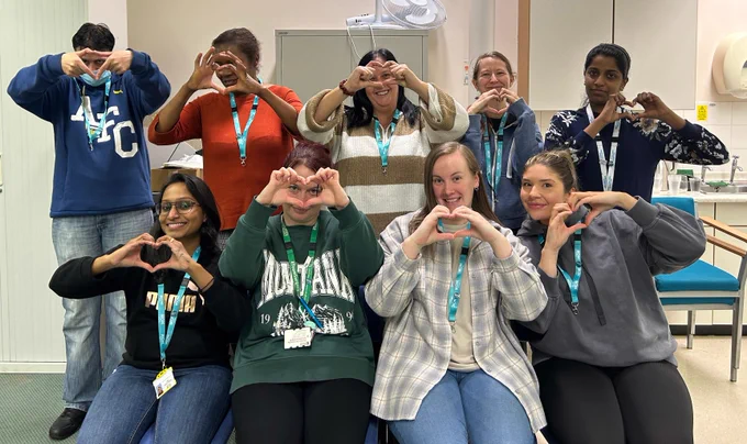 a photo of NHS staff all making a heart shape with their hands. Conflict resolution training.
