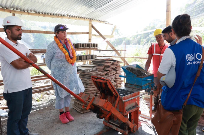 A man demonstrating brick making using climate friendly locally available materials to a woman and a man.  