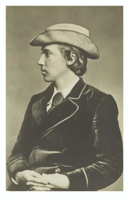 A side profile studio portrait of a young Robert Louis Stevenson in a hat, jacket and tie.