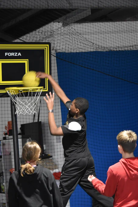 A player slam dunking a basketball while two others look on.