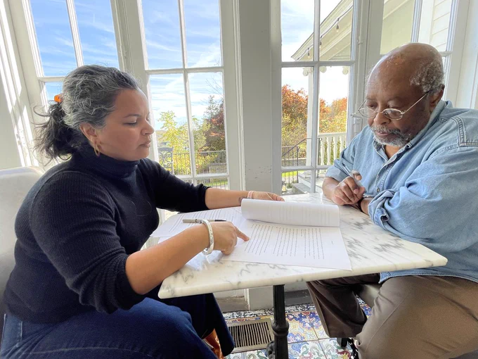 Photo of a 2024 Kweli fellow going over their work with author Edward P. Jones. 