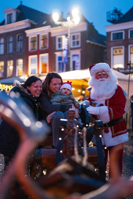 Bezoekers van Lichtjesavond 2023 poseren met de Kerstman op de Markt. 