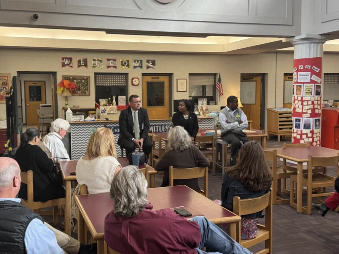 Three people in front of a group in school library