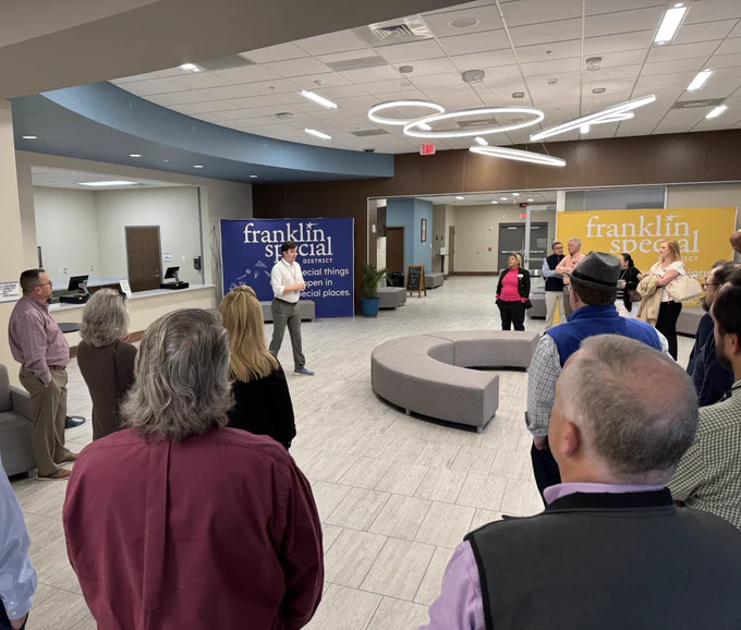 Group of people in theater lobby listening to a man speak