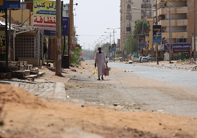 Man walks down the middle of a ruined street in Khartoum.