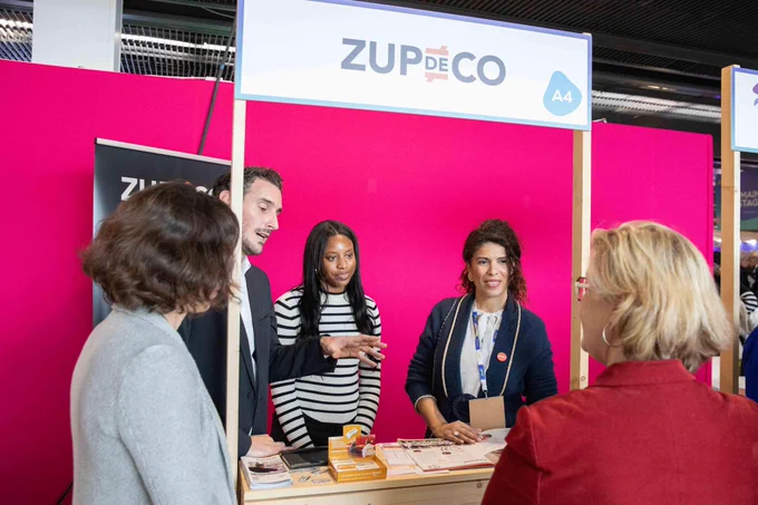 Marie-Agnès Poussier-Winsback échange avec les équipes de « Zup de Co » une association qui lutte contre les inégalités à l’école. En arrière plan, un fond rose fuchsia.