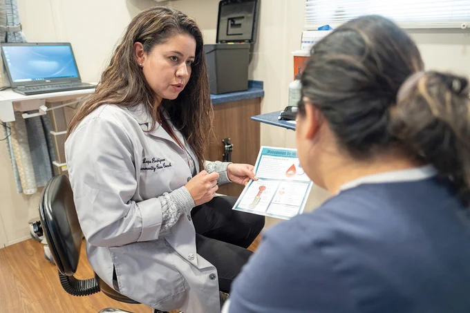 RFU Community Care Director Lupe Rodriguez speaks to a patient inside the care coach