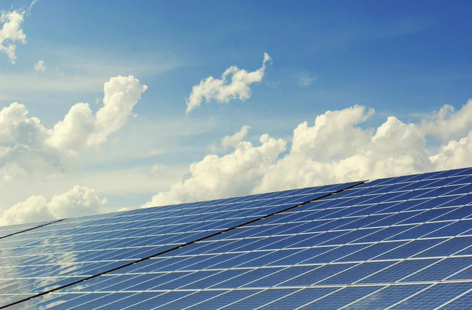 Solar panels arranged in rows with a clear blue sky in the background.