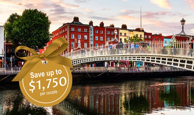 A photo taken at sunset of a walking bridge over a river in front of a row of houses. A gold emblem is superimposed over the photo that reads, "Save up to $1,750 per couple."