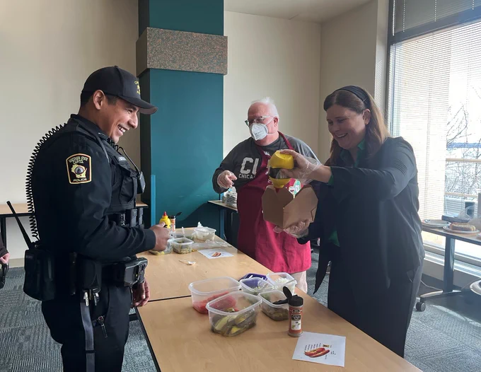 DOA Secretary Kathy Blumenfeld prepares a “to go” order for a Capitol police officer during the Chicago Hot Dog Day fundraiser for DOA’s Partners in Giving campaign.
