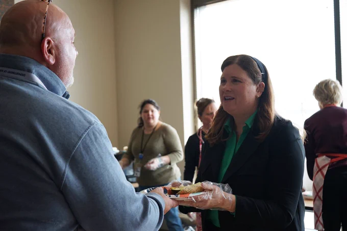 DOA Secretary Kathy Blumenfeld hands a hot dog to a colleague during the DOA Chicago Hot Dog Day fundraiser.