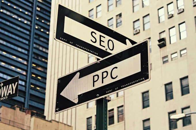 SEO vs PPC: Pros and cons for project websites - photo of 2 street signs, one pointing to SEO and one to PPC