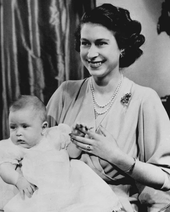 Black and white photograph of Queen Elizabeth II when Princess Elizabeth, holding on her lap Prince Charles as a baby.