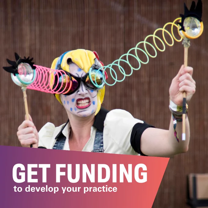 Performer with face paint holding colorful spiral spring toys at an event, with text overlay that says 'GET FUNDING to develop your practice.'