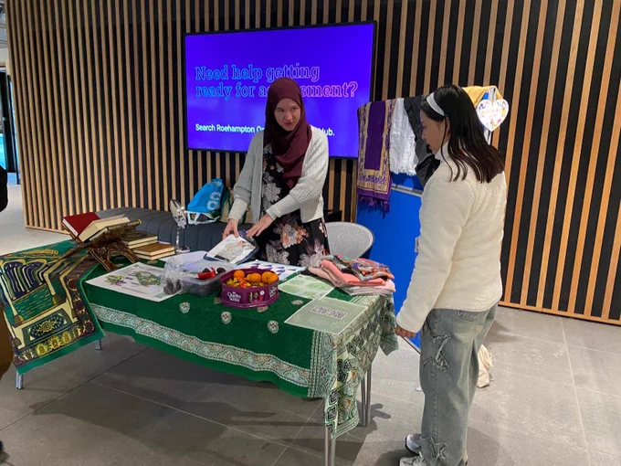 Image shows 2 students discussing at the stall
