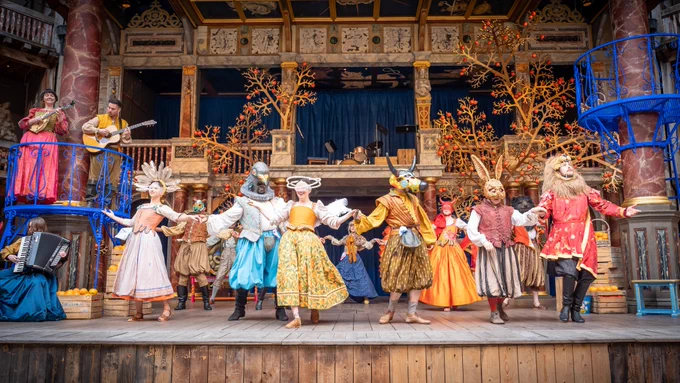 The Company of Much Ado About Nothing (2024). 

A group of actors wearing brightly coloured costumes dance on stage in the Globe Theatre. 

Photography by Marc Brenner. 