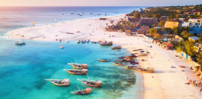 A coastline in Zanzibar with fishing boats on the water 