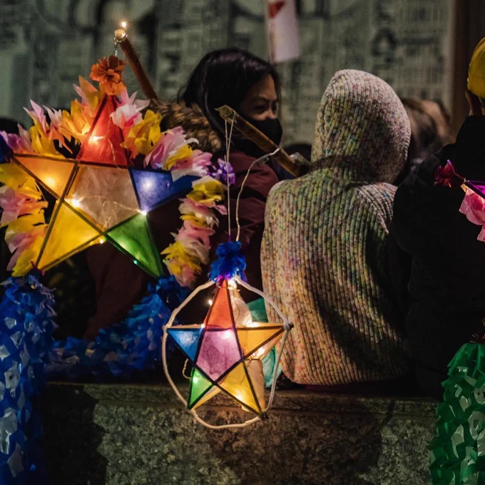 A group of people at the Parol Lantern Festival holding vibrant, star-shaped lanterns outside.