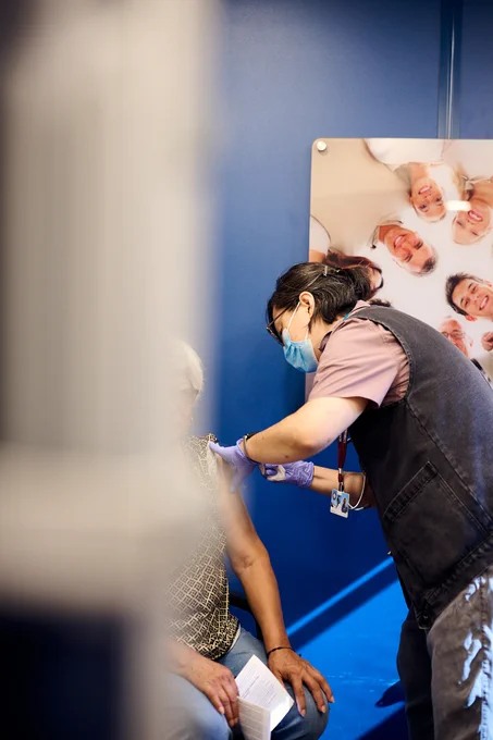 A patient receiving a vaccine inside the Care Coach. The camera angle does not reveal the face of the patient.