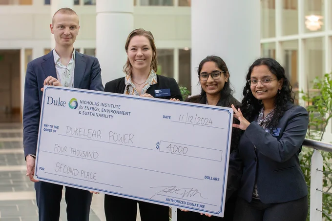 A team of graduate students from Duke University holds an oversized check for $4,000 for winning second place in the 2024 Energy in Emerging Markets Case Competition.